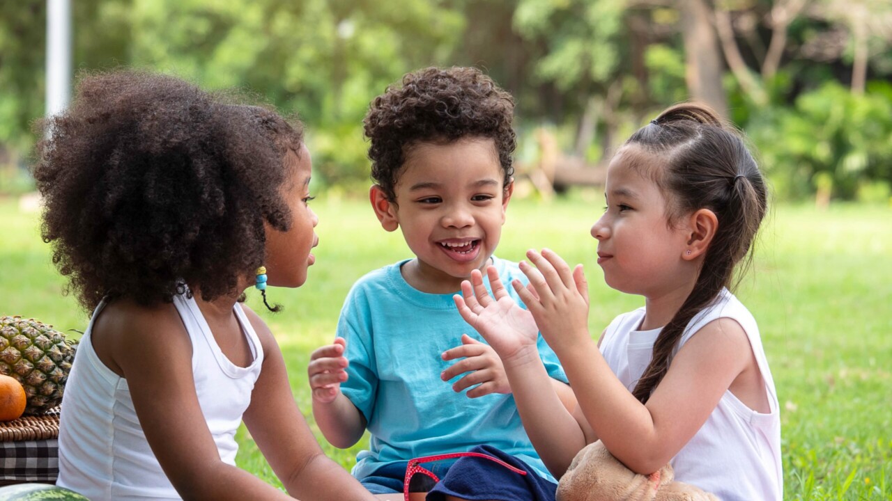 Group of kids sitting in a circle with a little girl clapping her hands.