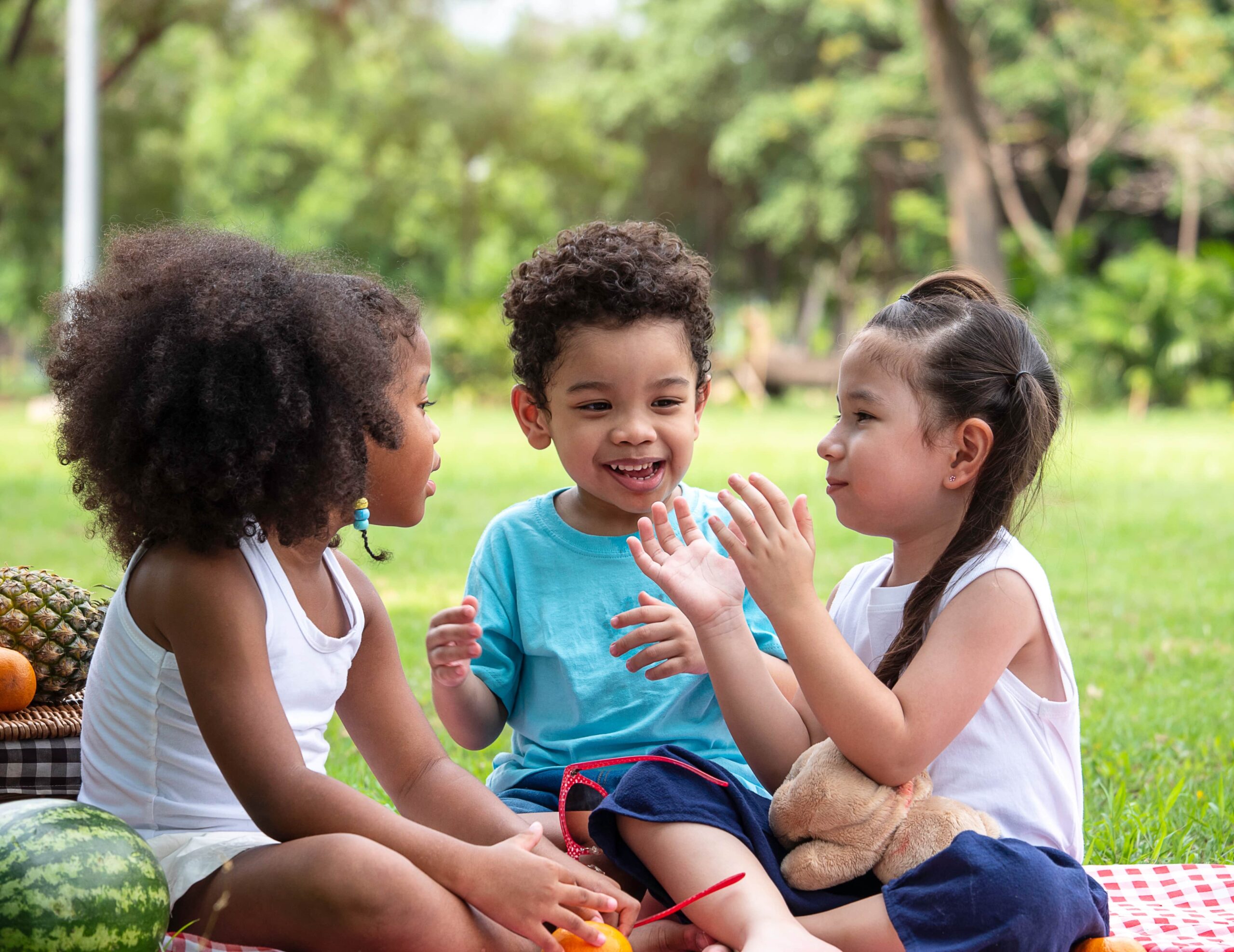 Group of kids sitting in a circle with a little girl clapping her hands.
